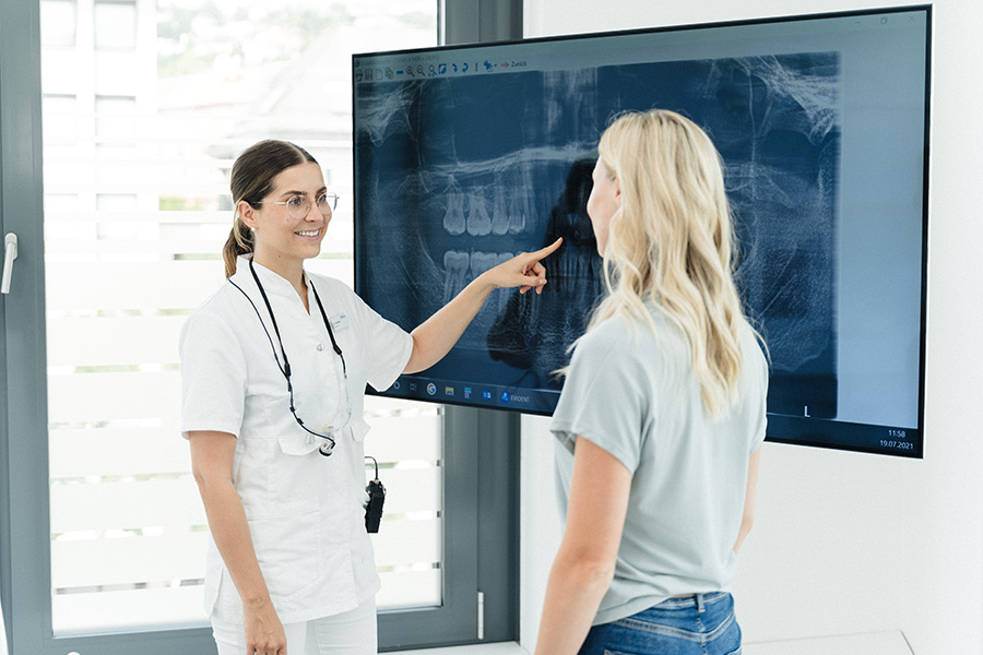 Ärztin und Patientin schauen Röntgenbild auf einem großen Bildschirm an